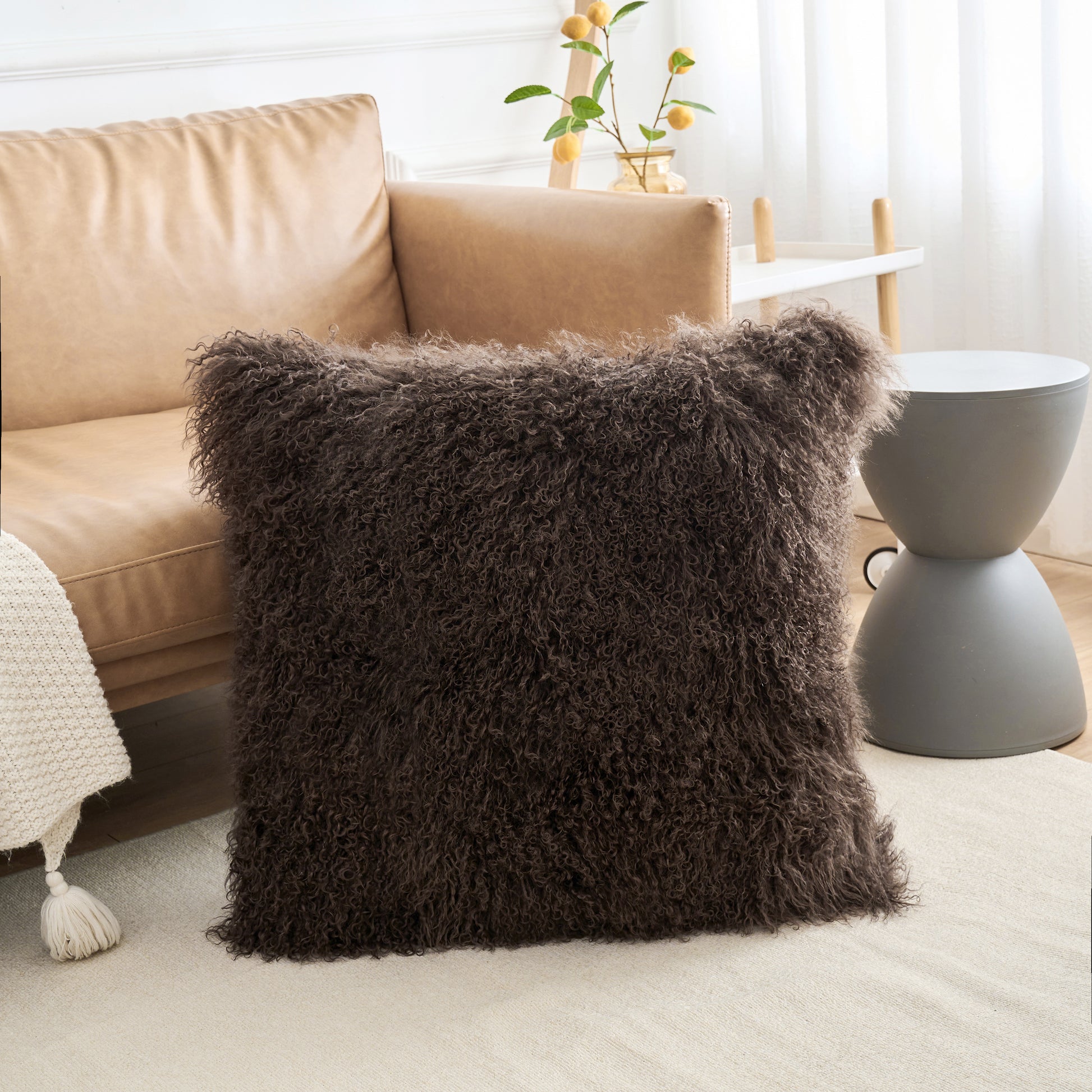 Close-up view of Mongolian lamb fur pillow in espresso brown on sofa showing soft fluffy curly wool texture in modern interior lighting