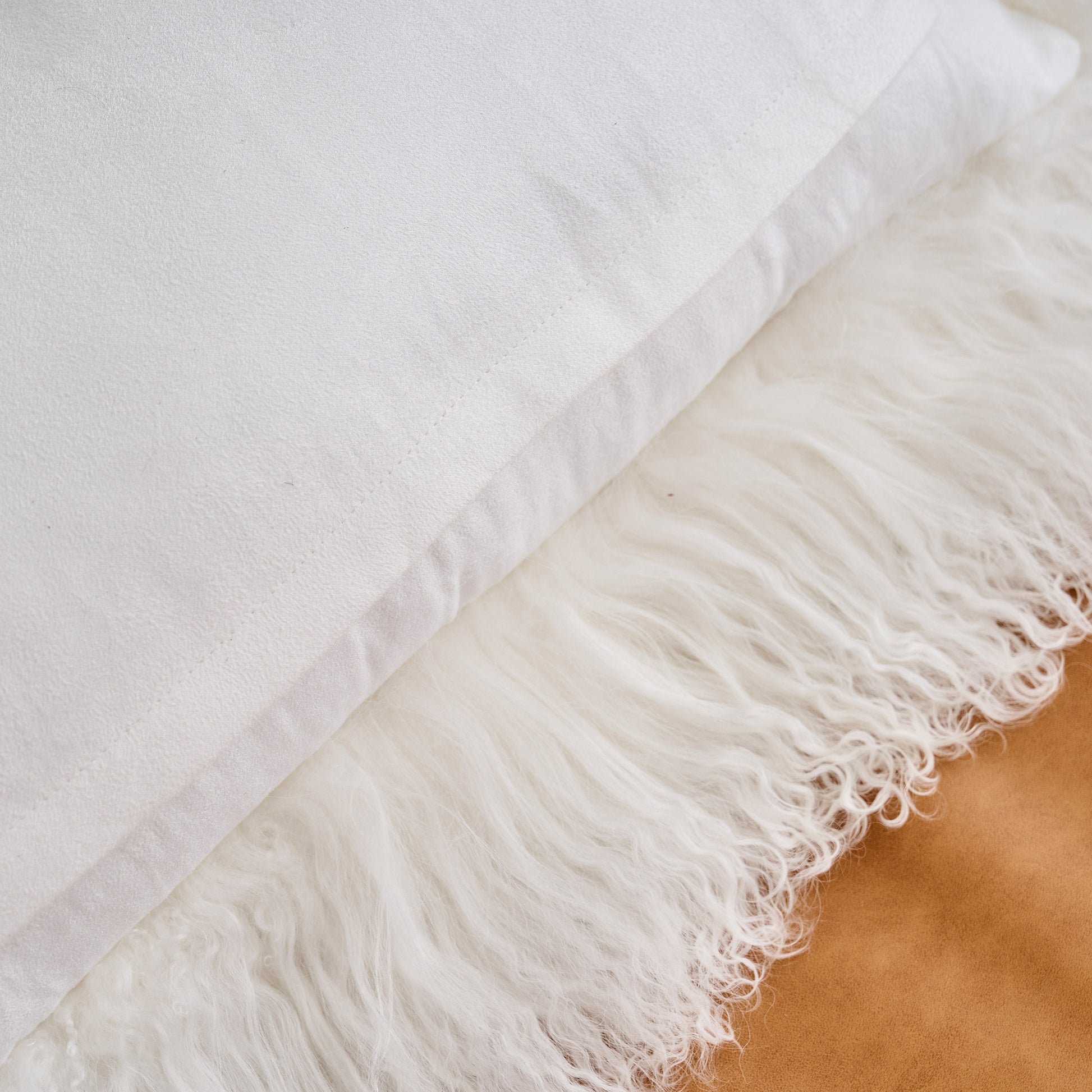 Back view of a white Mongolian lamb fur throw pillow with suede backing